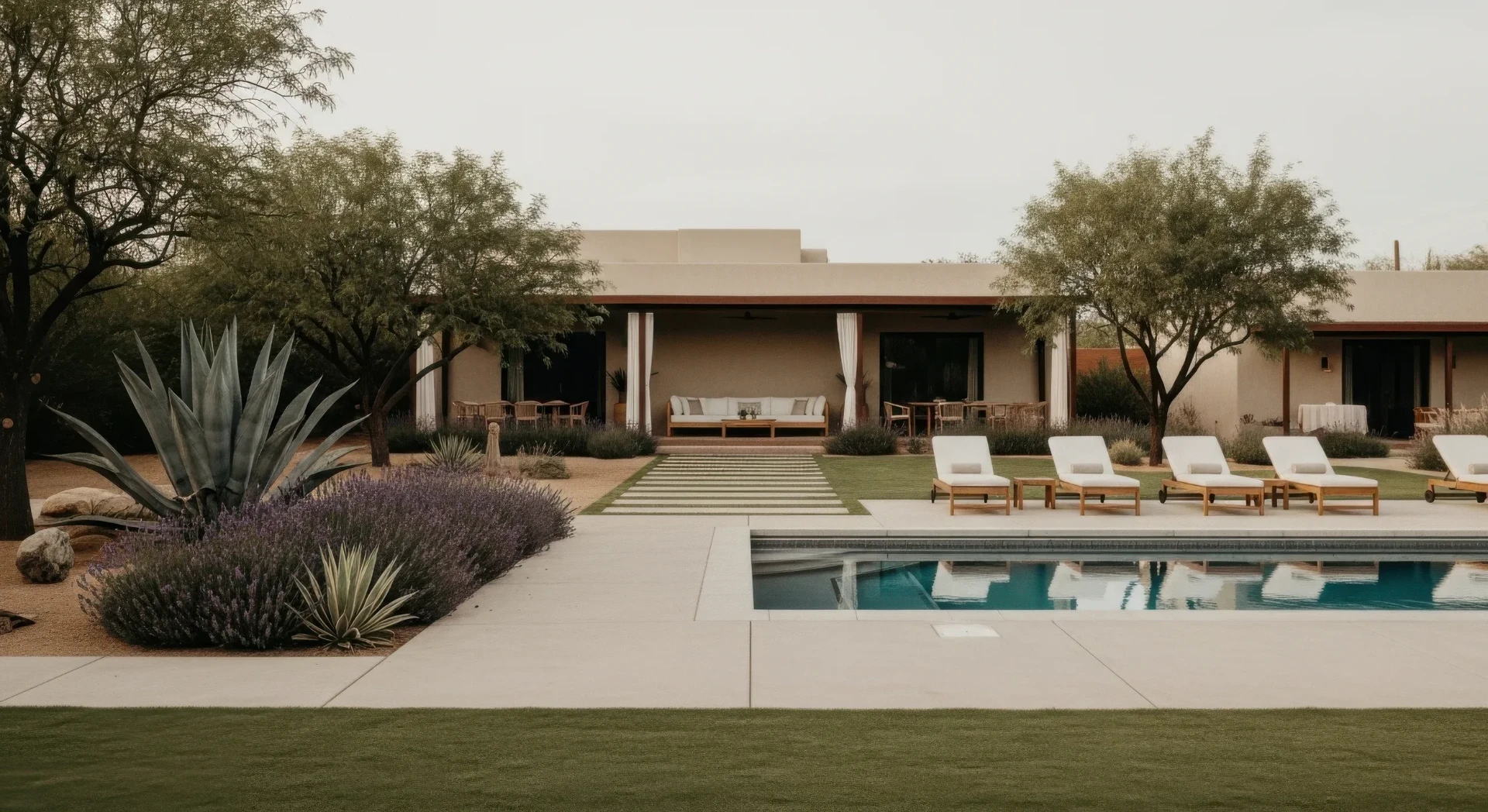Residential pool with white loungers beside a desert-modern home
